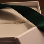 Gold diamond half eternity band in an open box with a green ribbon